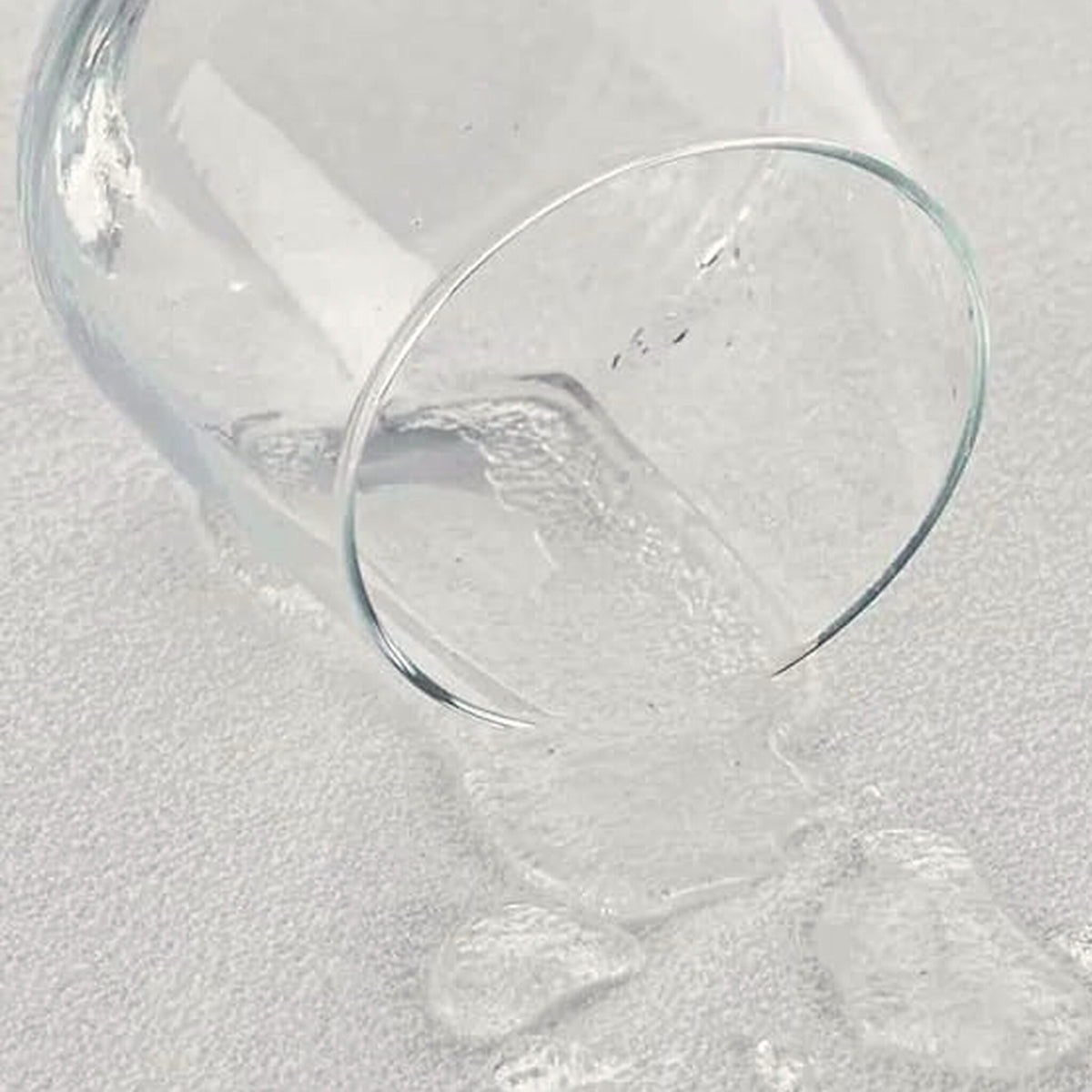 Wasser aus einem umgekippten Glas perlt auf der Oberfläche ab